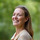 Usmívající se žena s klidným výrazem praktikující mindfulness meditaci v přírodě